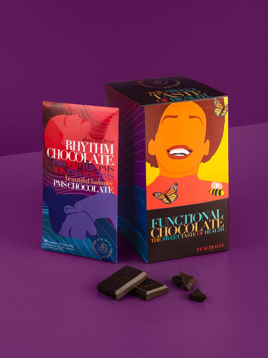 Two Rhythm Chocolate boxes on a purple background with some chocolate pieces.