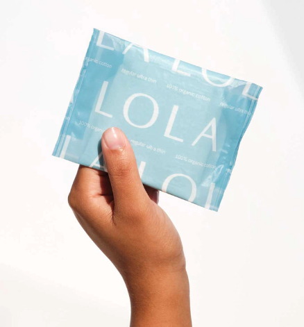 Hand holding a blue LOLA product packaging against a white background